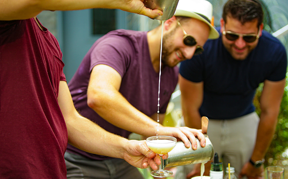 Workshop participant straining a cocktail into a coupe glass
